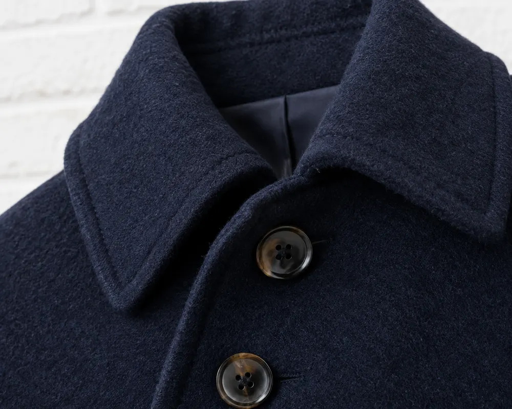 Detalle del cuello de un chaquetón de paño azul marino con botones oscuros de cuatro agujeros